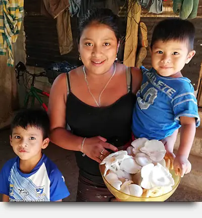 A photo of a mother and her children with mushrooms for a micro-business.