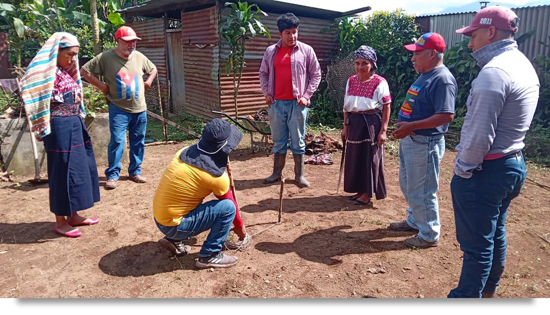 Imagen de los miembros del equipo de Semillas para un Futuro ayudando a los nuevos participantes en el programa a plantar su propio huerto de permacultura.
